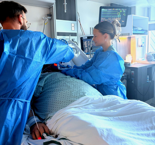 Un jeune homme et une jeune femme prennent soin d'un patient alité.