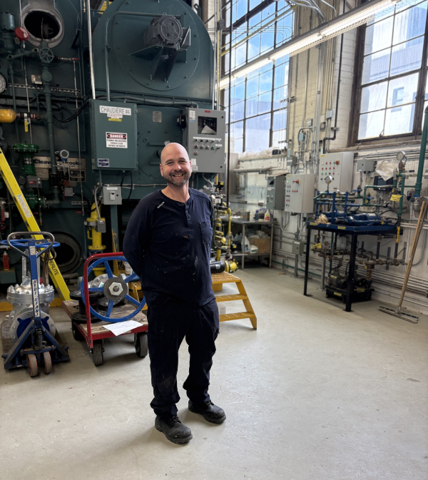 Kevin Moon devant l’une des nombreuses chaudières à vapeur alimentant les bâtiments du CHUL. Source : Service des communications. Photo de Kevin Moon devant l'une des immenses chaudières à vapeur du CHUL.
