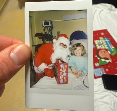 Une main tient la photo d'une patiente prise avec le Père Noël.