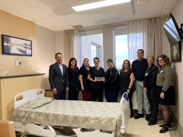 La chambre d'aide médicale à mourir de l'Hôpital Saint-François d'Assise. Sur la photo, de gauche à droite : Francis Morin, vice-président exécutif à la Fondation du CHU de Québec; Dre Sophie Breton, adjointe local à la cheffe du Service de soins palliatifs HSFA; Caroline Grégoire, cheffe d’unité de soins infirmiers B5-B8 HSFA; Josée Létourneau, infirmière auxiliaire; Julie Gamache, infirmière clinicienne; Amélie LeBrasseur, agente de planification, de programmation et de recherche à la DMSP; Simon Noël, technicien en bâtiment, DST; Geneviève Proulx, coordonnatrice médecine et cardiologie à la Direction médecine; Audrey Gagnon, directrice de la Direction médecine. L'équipe qui a rendu l'aménagement possible à HSFA.