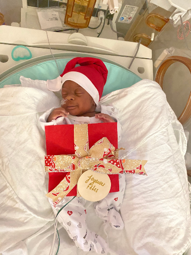 Un bébé de l'unité néonatale déguisé en cadeau.