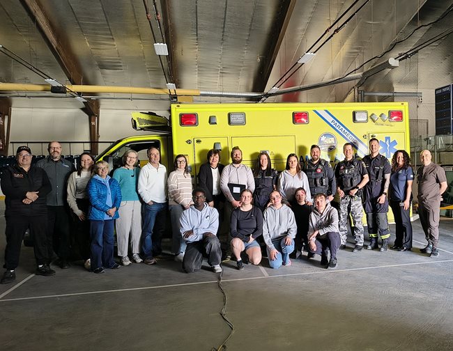 Groupe de personnes alignées devant une ambulance.