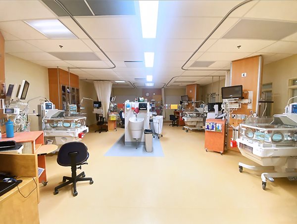 Une grande pièce contenant plusieurs incubateurs, ordinateurs et équipements médicaux. Au milieu se trouve un lavabo.