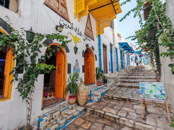 Une petite rue dans la médina de Sousse. Source : Getty Images. Une rue aux maisons blanches, bleues et jaunes.