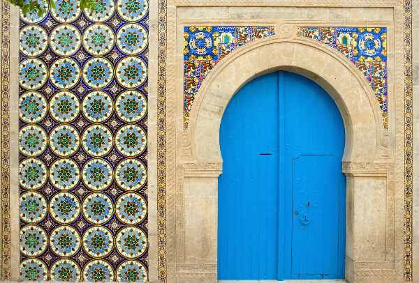 Une maison dans la médina d’El Jem, ornée de magnifiques carreaux de céramique. Source : Getty Images. Une maison avec une porte bleue et des carreaux de céramique.